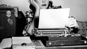woman inspecting typewritten sheet of paper