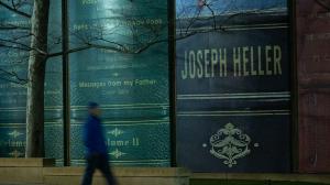 night photo of man walking past huge books